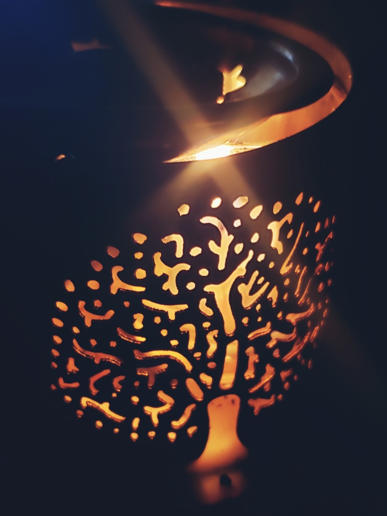 Scent burner features a tree of life that us highlighted from the candle burning inside